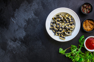 pasta farfalle with cuttlefish ink (healthy eating, black multi-colored) menu concept. food background. top view. copy space