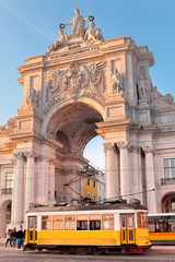 Lisbon, Portugal, a traditional yellow tram passing in front of the Rua Augusta Arch at sunset