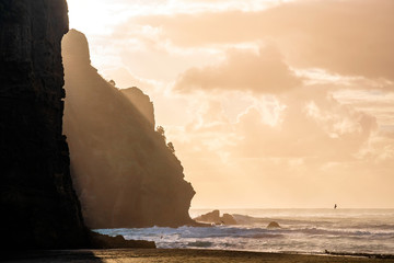 View of waves crushing in Piha beach cove with Camel Rock in background