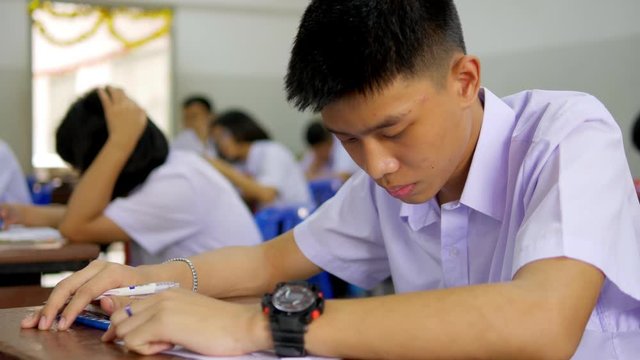The Asian high school students in white uniform are doing examinations.
