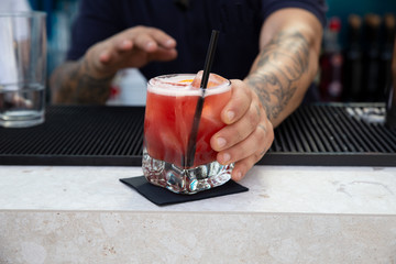 Fototapeta na wymiar Barman delivering a tasty cocktail in a bar.