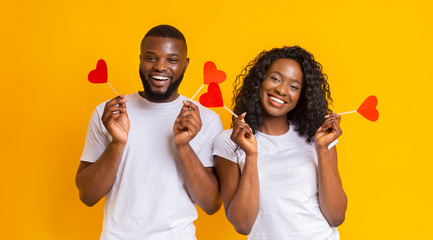 Lovely afro couple holding red heart shaped cards