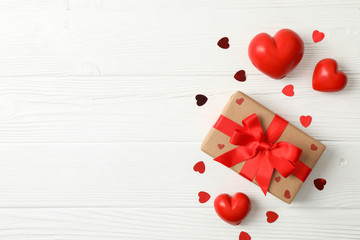 Gift box and hearts on wooden background, space for text