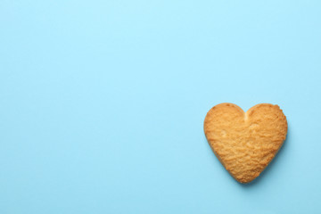Heart shaped cookie on blue background, space for text