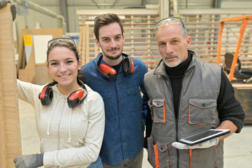 Portrait of man with trainees in carpentry warehouse