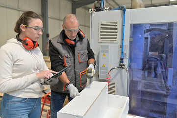Carpenter with apprentice working in workshop