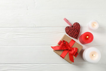 Gift box, candles and heart on white wooden background, space for text