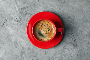 Red cup of coffee on grey background, top view