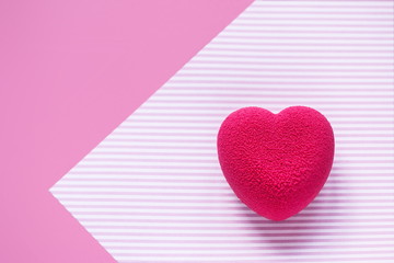 Valentines day concept. Pink velvet heart shaped cake on on a pink striped surface. 
