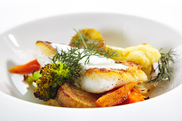 Cod Fillet with Baked Vegetables on White Restaurant Plate Isolated
