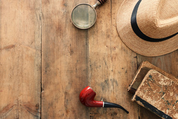 Concept image of investigation or private detective. Fedora hat, magnifying glass and vintage items...