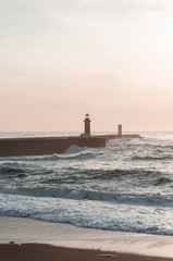 Fototapeta premium Ocean at sunset, behind the lighthouse. Lighthouse as a Landmark. Vertical photo