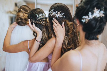 The bridesmaids and the bride straighten their hairstyles and hold on to their hair. Morning of the bride with best friends. Wedding bachelorette party. Photography, concept. - obrazy, fototapety, plakaty