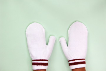 Two hands in white mittens isolated on a light background