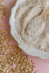 Oat food ingredients - flour and flakes on pink background