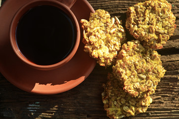 Oatmeal cookies with apples. Coffee in a rustic cup on a wooden background