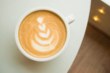 Cup of cappuccino with beautiful latte art on a wooden table in a cafe with copyspace.