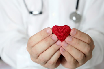 Cardiology and health care, doctor holding red knitted heart in hands. Concept of cardiologist,...