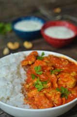 Butter chicken with rice in a white bowl on a gray wooden background