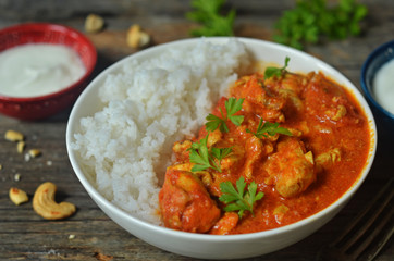 Butter chicken with rice in a bowl on a wooden background