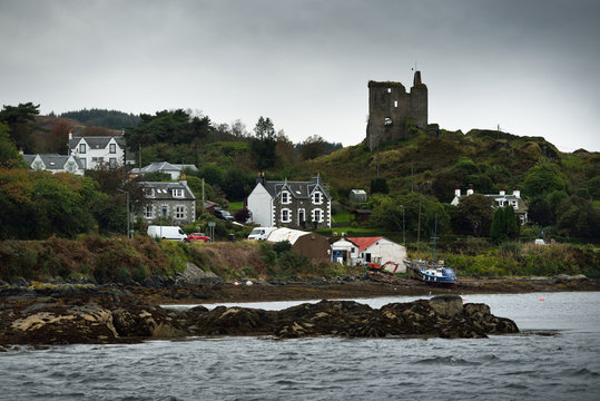 A view of the shores of Tarbert from the water. Country houses, yachts and fishing boats close-up. Scotland, UK