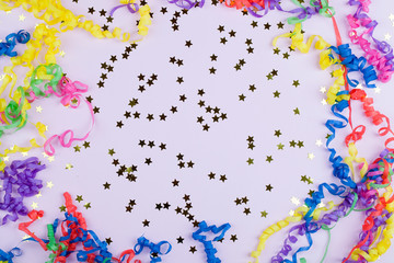 Festive party border or frame of colorful spiral streamers and confetti on pink background