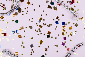 Festive party border or frame of silver spiral streamers and confetti on pink background