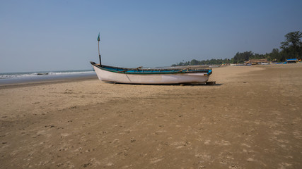 Empty boat on sandy beach in bright day. Large old white boat on sandy seaside ready to sail in bright day on beach