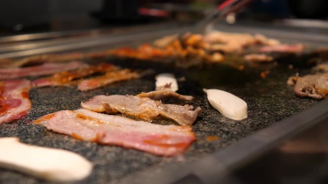 Close-up of woman's hand coocking korean barbecue in a restaurant