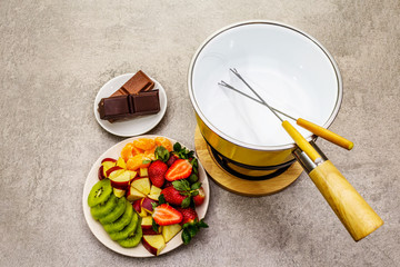 Chocolate fondue. Assorted fresh fruits, two types of chocolate. Ingredients for cooking a sweet romantic dessert. Stone concrete background