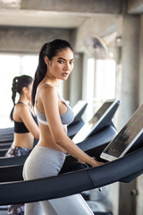 Attractive asian sport women running on treadmil with friend in sport gym