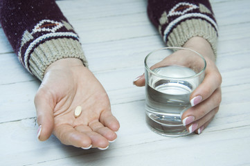 Pills in hand and a glass of water. Disease.