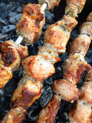 Close view on pork meat cooked outdoor on metal skewers