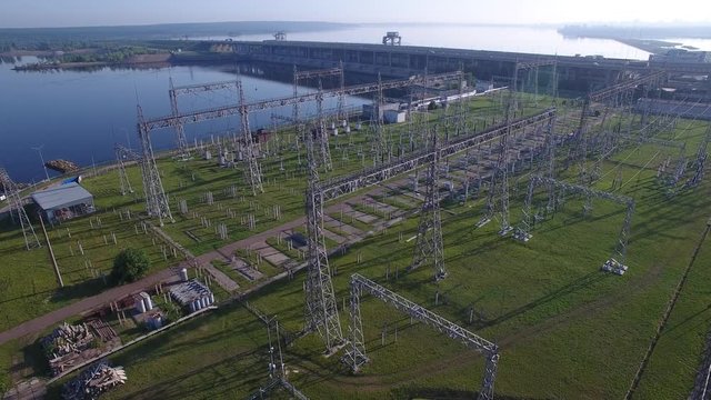 Electric substation, hydroelectric power station, bridge over river, electric tower, power distribution. Cars and trucks traffic, fog early morning spring summer sun. Aerial quadrocopter flying over.