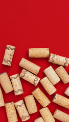 Background with wine corks on red colored paper with copy space. Close up used wooden stoppers. Concept for red wine, vertical format.