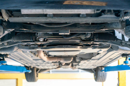 chassis bottom view and power steering rack and suspension system of saloon or sedan car at garage lift up for maintenance