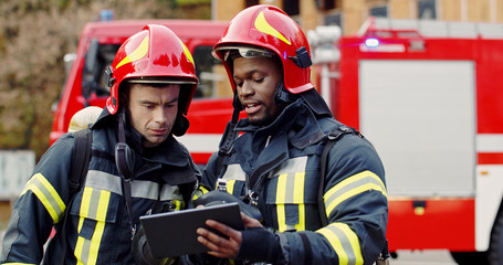 Portrait of two firefighters in fire fighting operation, fireman in protective clothing and helmet...