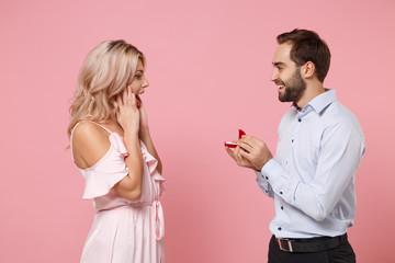 Excited young couple two guy girl in party outfit celebrating posing isolated on pastel pink wall background. Valentine's Day Women's Day birthday holiday concept. Hold present box with proposal ring.