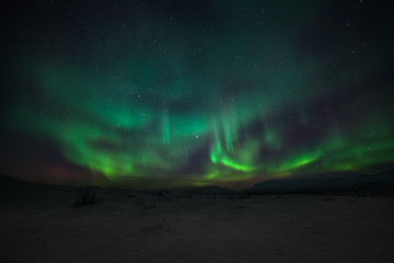 Dramatic polar lights, Aurora borealis with many clouds and stars on the sky over the mountains in the North of Europe - Abisko, Sweden. long shutter speed.