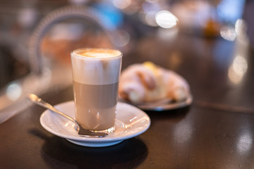 Foamy Caffelatte in a glass, on the wooden counter of a bar, in Rome