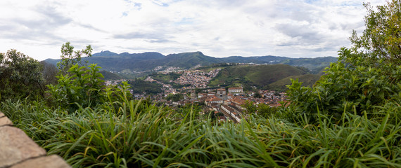 Panoramic landscape with historic colonial city of Ouro Preto seen from the São Sebastião viewpoint with Itacolomi mountain in the background on an overcast morning