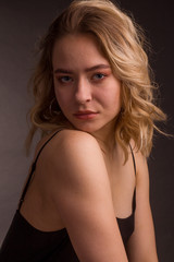 Fototapeta premium Studio portrait of blonde on a dark background in a dark dress
