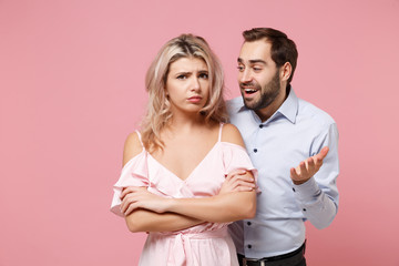 Dissatisfied couple two guy girl in party outfit celebrating posing isolated on pastel pink background. Valentine's Day Women's Day birthday holiday concept. Hold hands folded in prayer, apologizing.