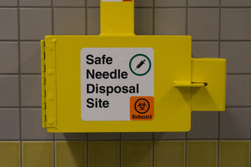 Safe medical needle disposal container on a toilet wall