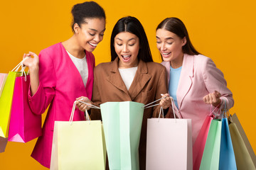 Three Excited Girls Looking Into Shopper Bags, Studio Shot