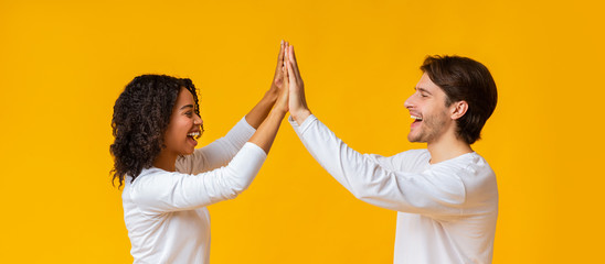 Cheerful multiracial couple giving high five to each other and laughing