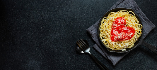 Spaghetti pasta with heart shaped tomato sauce, served in a pan. Dinner for Valentine's Day. Food with love. Top view, flat lay, black background