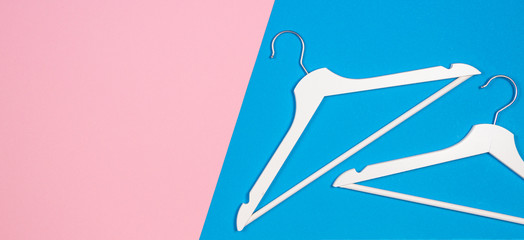 Two white wooden clothes hangers on pastel pink and light blue background. Shopping, sale, promo, social media, new season concept