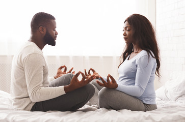 Pregnant woman doing yoga with her husband at home