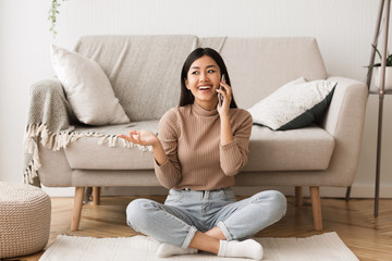Overjoyed asian girl talking on cellphone with friend